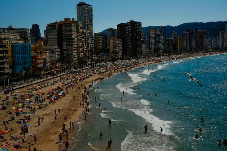 People enjoy a summer's day along the beach in Benidorm