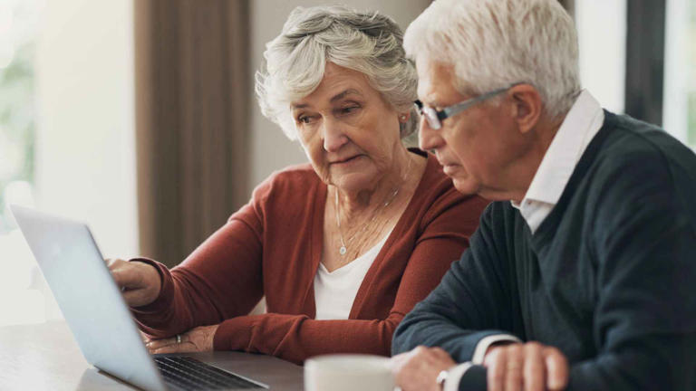 Laptop, finance and investment with a senior couple planning their retirement together in their home living room. Accounting, banking or budget with an elderly man and woman updating their portfolio