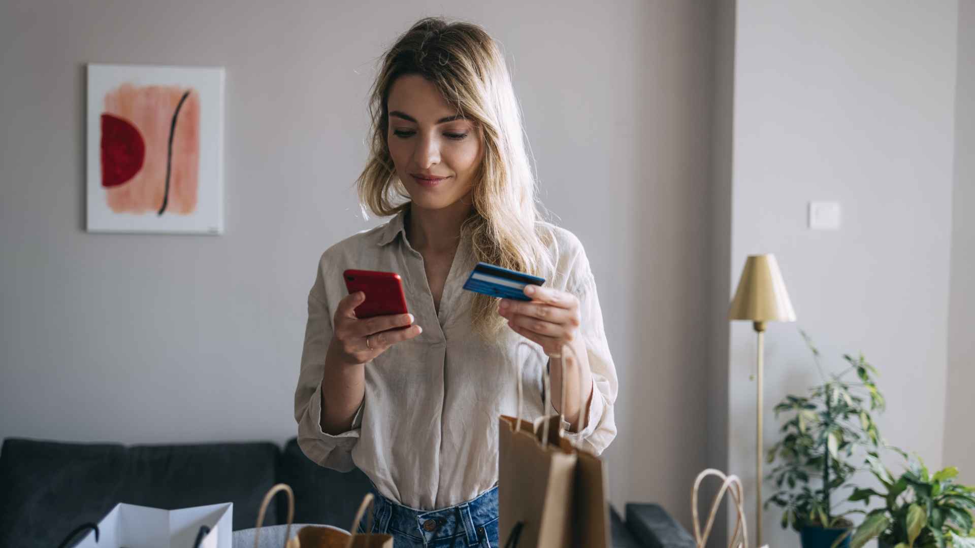 Smiling Woman Using Mobile Phone and Credit Card for Online Shopping from Home