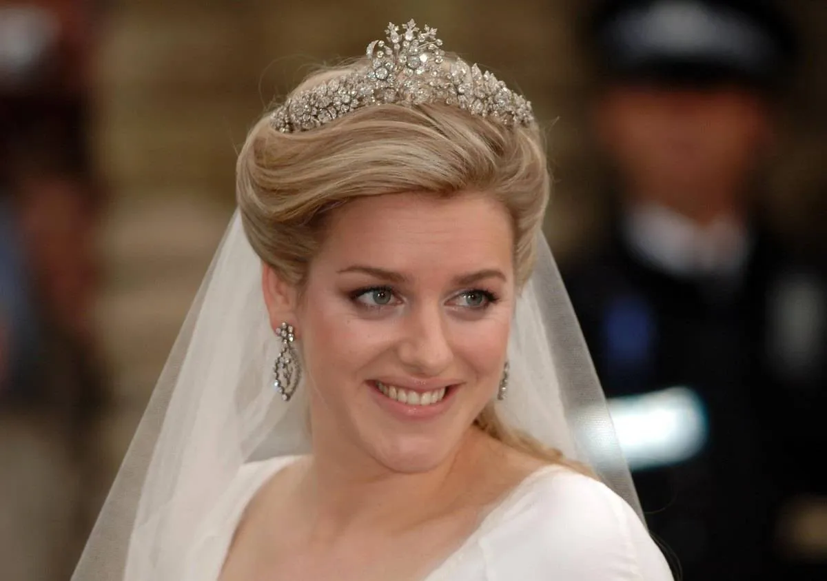 <p>Laura Lopes is the daughter of Camilla and Camilla's former husband, Andrew Parker Bowles. King Charles is her stepfather.</p> <p>For her 2006 marriage to Harry Lopes, Laura topped off her look with the <a href="https://www.thecourtjeweller.com/2017/02/the-cubitt-tiara.html" rel="noopener noreferrer">Cubitt-Shand Tiara</a>. It belongs to Camilla, who wore it on the day she married Laura's father, Andrew! The tiara belonged to Camilla's grandmother, Sonia Keppel, who left it to daughter Rosalind (Camilla's mother) upon her death.</p>
