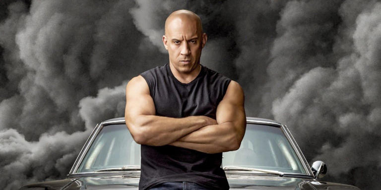 Dominic Toretto crosses his arms in front of black smoke from Fast & Furious 