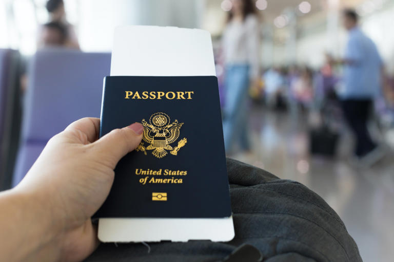 A person is seen holding a U.S. passport. -lead