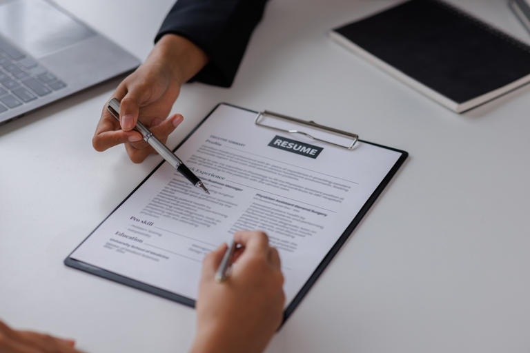 Two people review a resume, including a skills list. Emphasizing the right skills on your resume can help you stand out against other applicants.