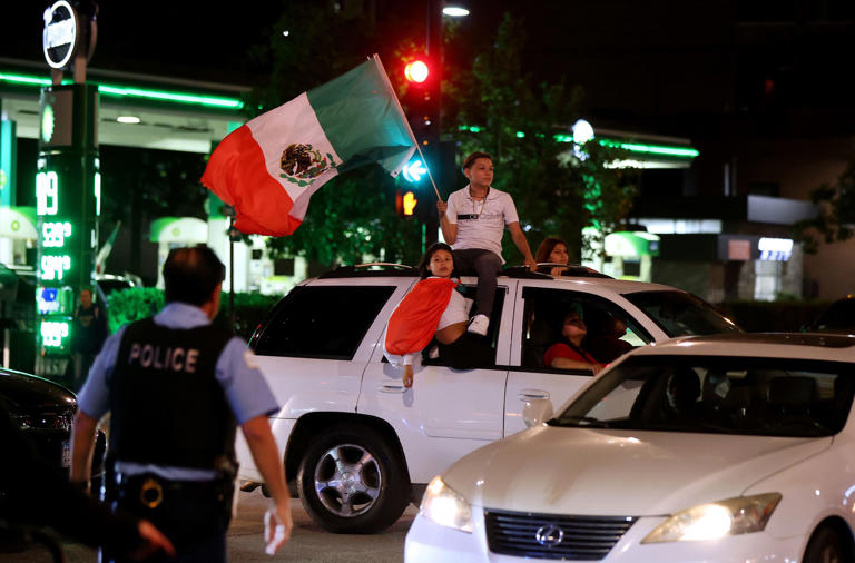 A group celebrating Mexican Independence Day moves in a vehicle down Roosevelt Road at Wabash Avenue as Chicago police stationed at that corner block vehicles from going downtown on Sept. 16, 2023.