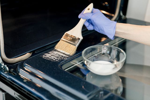 spreading baking soda paste in the oven