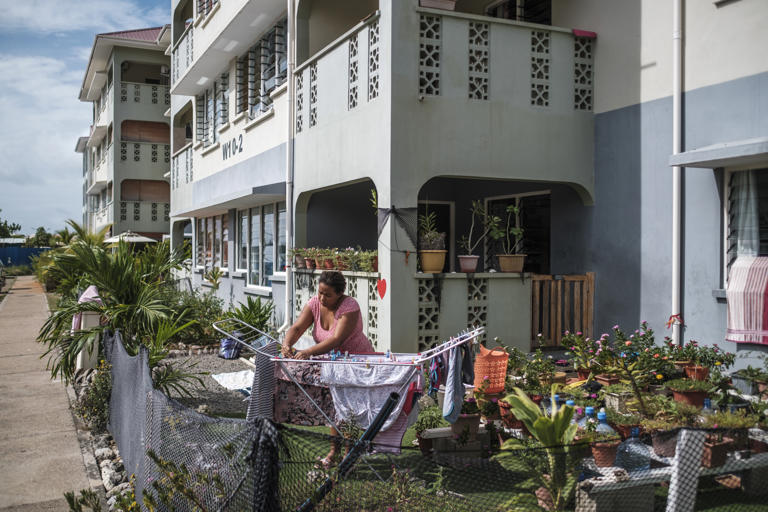 A woman hangs clothes to dry in her garden. She is one of thousands of Seychellois who live in housing built by China and made available at subsidized prices.
