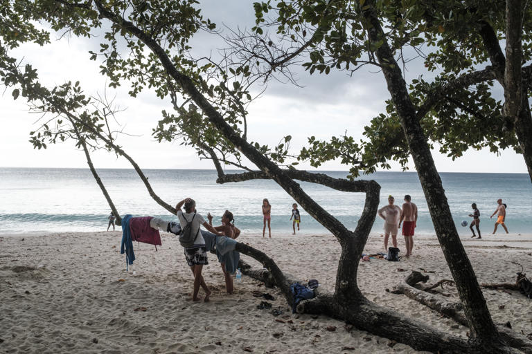 People hang out on the beach in the touristic area of Beau Vallon, on the island of Mahe.