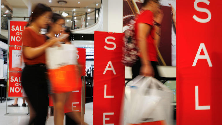 People shop in mall with "sale" signs. Sale Lead