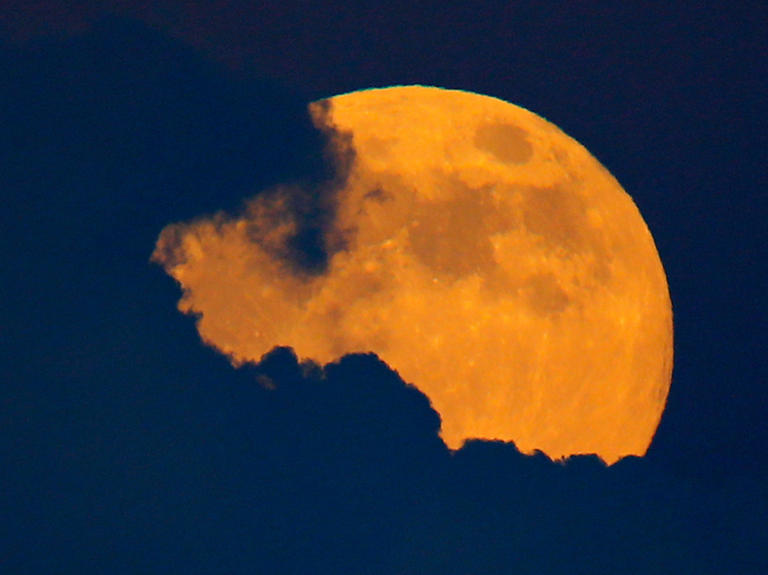 A full moon, also a harvest moon, rises past thunder clouds near Encinitas, California September 8, 2014. REUTERS/Mike Blake