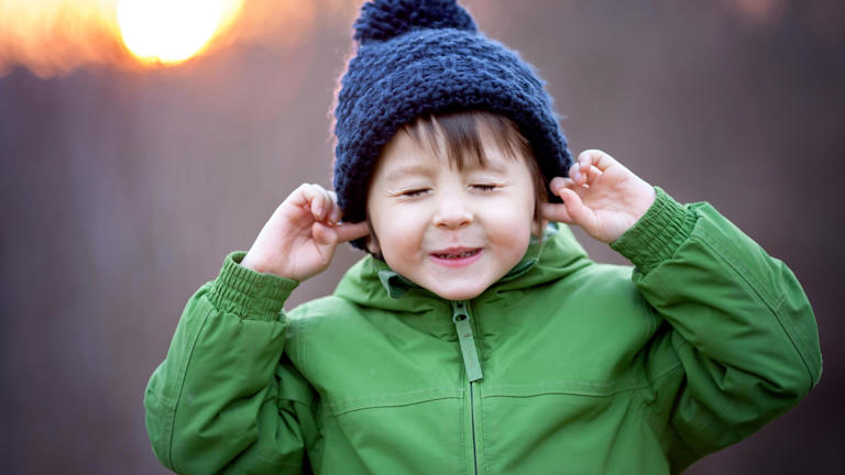 little kid closing eyes and plugging ears with their fingers