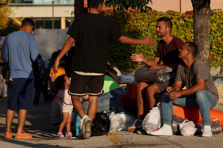 Migrants who arrived on buses from Texas rest before being transported to shelters citywide at an arrival area in the 500 block of West Vernon Park Place, Oct. 3, 2023, in Chicago.
