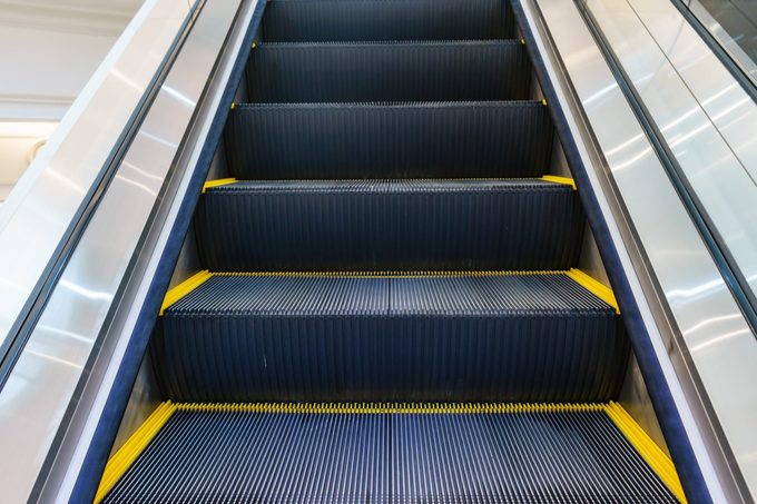 Escalator in Community Mall, Shopping Center. Moving up staircase. electric escalator. Close up to escalators. Close up floor platform. yellow bands. metal line steel. yellow gray steel line.