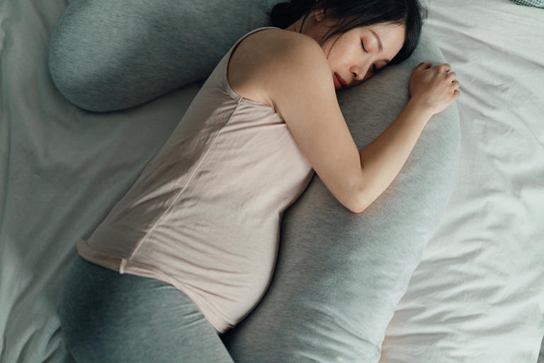 Pregnant Woman Sleeping In Bed With Pillows