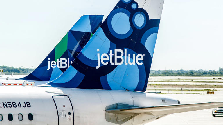 Two JetBlue planes sit next to each other. Lead
