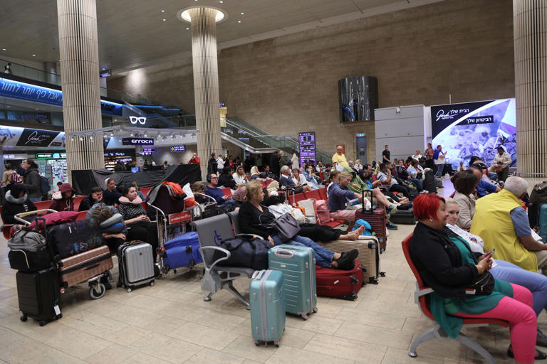 Passengers wait at Ben Gurion Airport near Tel Aviv, Israel, on October 7, 2023, as flights are canceled because of the Hamas surprise attack. The conflict sparked major disruption at Tel Aviv airport, with American Airlines, Emirates, Lufthansa and Ryanair among carriers with canceled flights.