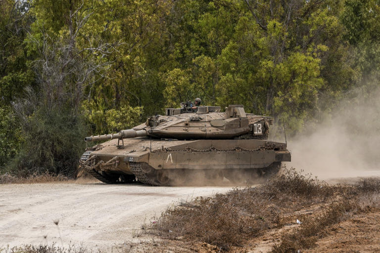 Izraeli harckocsi gyülekezési pontra tart az Izrael és a Gázai övezet határának térségében, Dél-Izraelben 2023. október 9-én