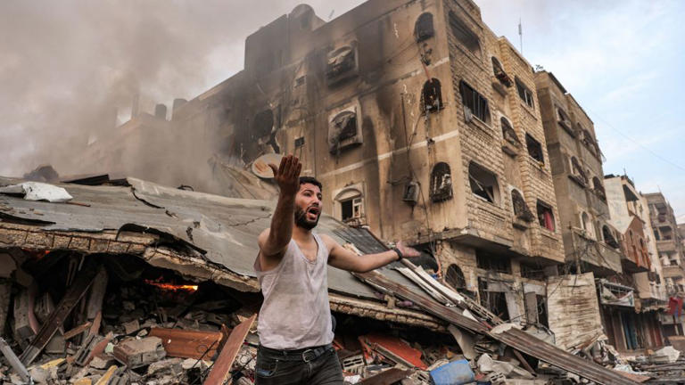 A man reacts outside a burning collapsed building following Israeli bombardment in Gaza City on October 11. - Mohammed Abed/AFP/Getty Images