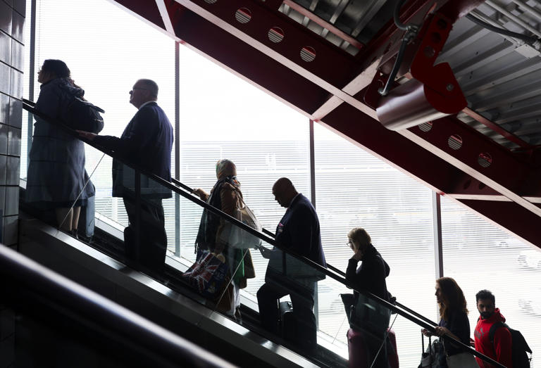 Passengers ride an escalator from the Airport Transit System to Terminal 3 at O'Hare International Airport on Oct. 20, 2023.