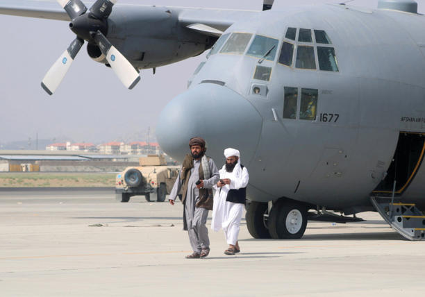  TALIBAN MEMBERS walk in front of a military airplane a day after the US withdrawal, in Kabul, August 31, 2021. 