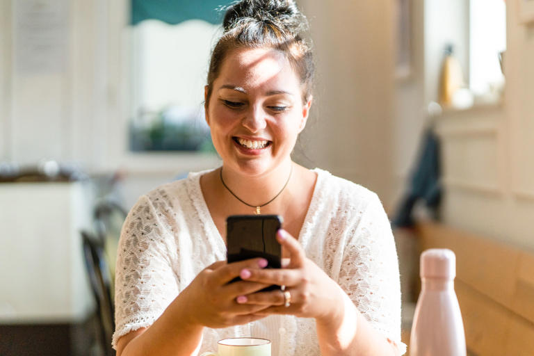 smiling woman texting long distance friend