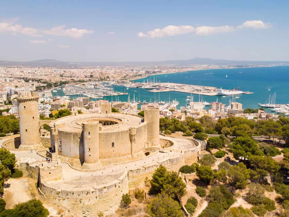 "Aerial view of Bellver Castle, a circular fortress atop a hill, overlooking the city of Palma, Mallorca.