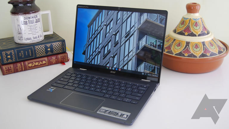 The Acer Chromebook Spin 714 on a white table with some books and a pot behind it.