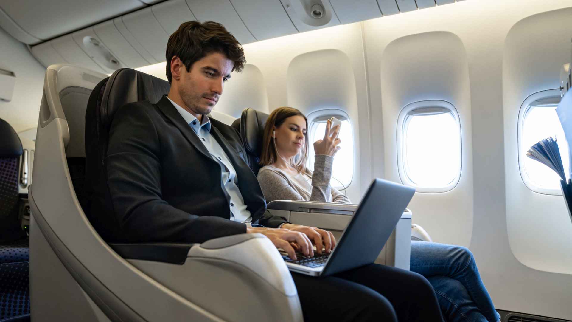 Business man traveling by plane and working on his laptop