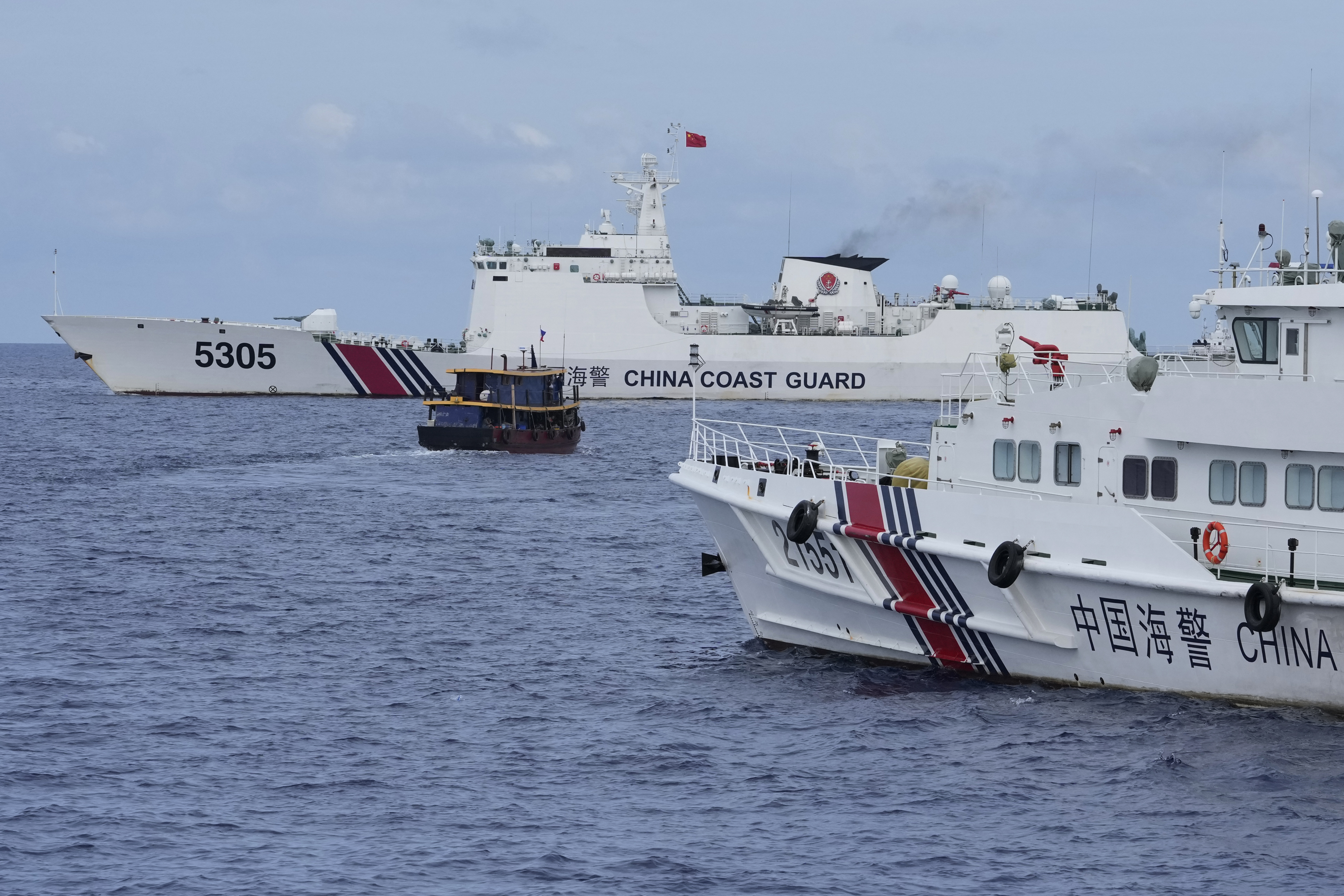 A Philippine supply boat, center, maneuvers around Chinese coast guard vessels as they try to obstruct its passage near the disputed Second Thomas Shoal, locally known as Ayungin Shoal, in the South China Sea on Aug. 22.