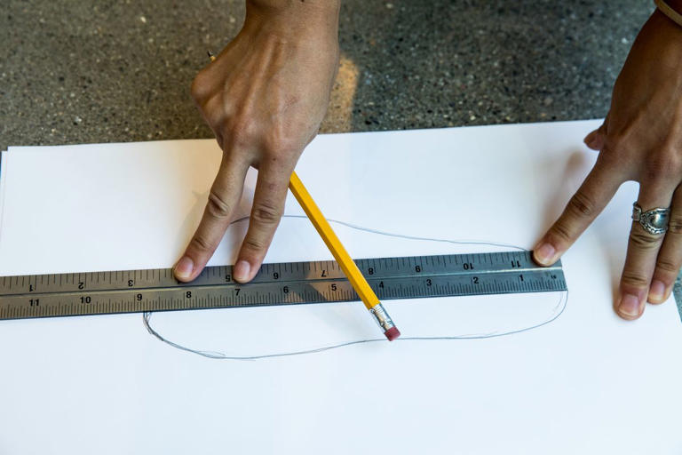 using a ruler to measure outline of foot on paper