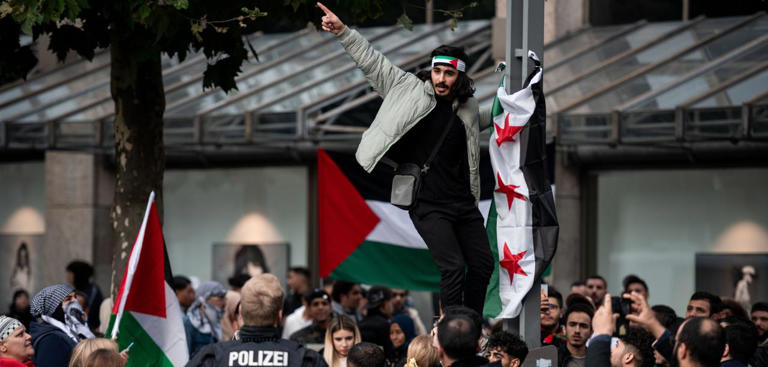 Bochum, 18. Oktober: Ein Teilnehmer einer Anti-Israel-Demonstration hängt eine Fahne auf dpa