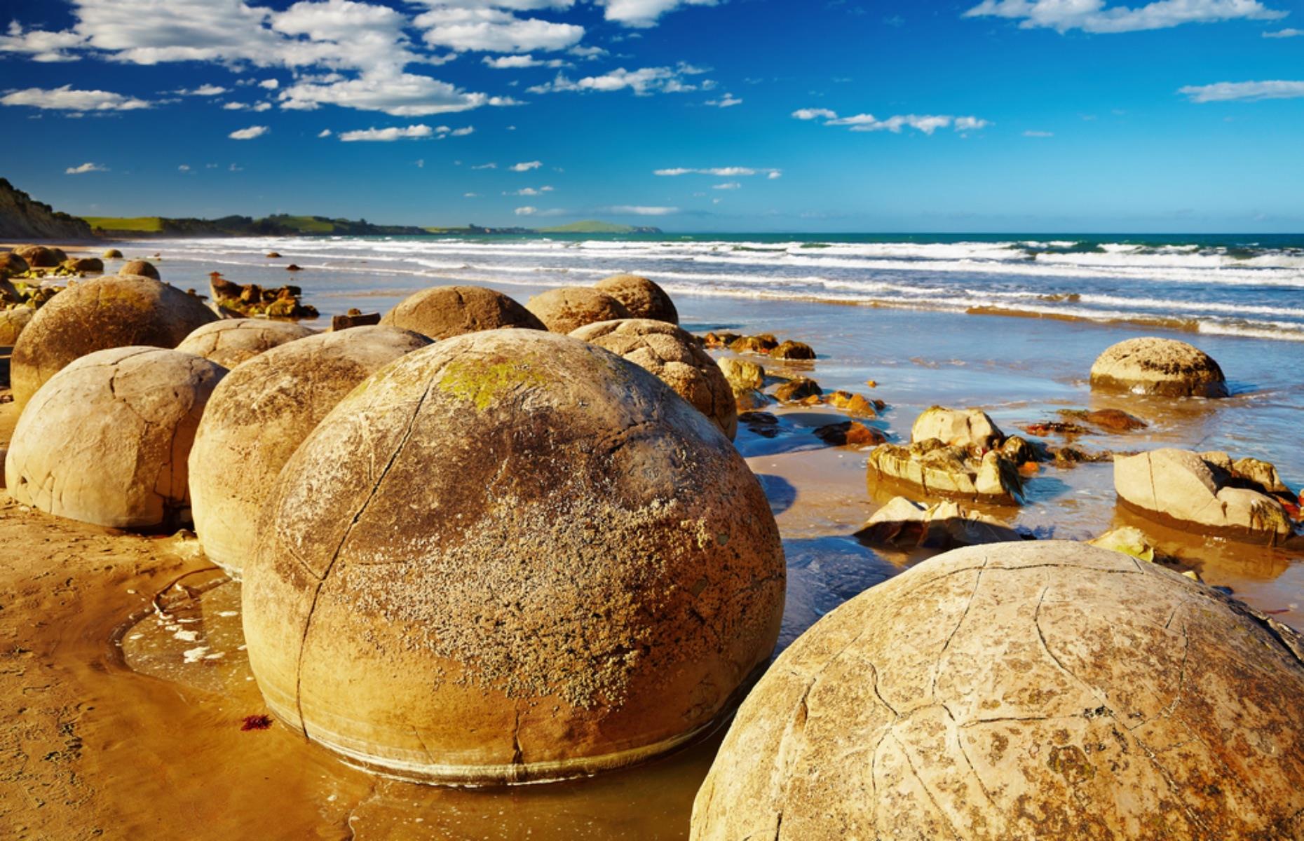 <p>These huge, bulbous anomalies scattering the sand of Koekohe Beach, between the towns of Moeraki and Hampden, add a different dimension to South Island’s scenic North Otago coast. Appearing like giant cannonballs up to 6.5 feet high, the geologic wonders look as though they were carved by human hands, but in fact they are made of calcified rock concreted together 65 million years ago and slowly released from the soft seabed by coastal erosion. Similar Koutu Boulders can be found around Hokianga Harbour on North Island.</p>