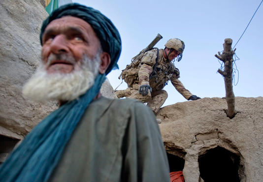 Pvt. Richard Boutet, 38, of Quebec City searches a compound as the owner Fazel Mohammad, left, looks on during an operation in the Panjwaii district of Kandahar province, Afghanistan on June 30, 2011. (David Goldman/The Associated Press)
