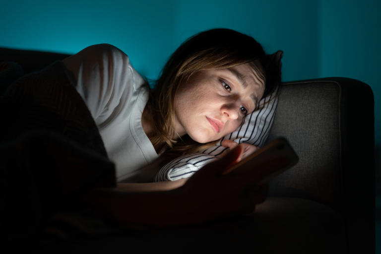 Stock image of a woman staying up late on her phone.