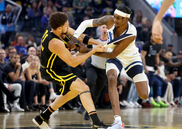 Golden State Warriors' Klay Thompson and Minnesota Timberwolves' Jaden McDaniels entangle each other as they pull their jerseys in the first quarter at Chase Center in San Francisco on Tuesday, Nov. 14, 2023.