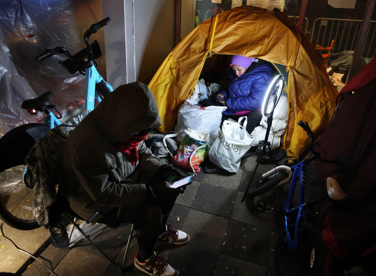 Yessica Karolina Badell Palmar, right, a migrant from Venezuela, is seen in her tent outside the Chicago police 1st District station on South State Street as as cold temperatures take hold on Oct. 30, 2023.
