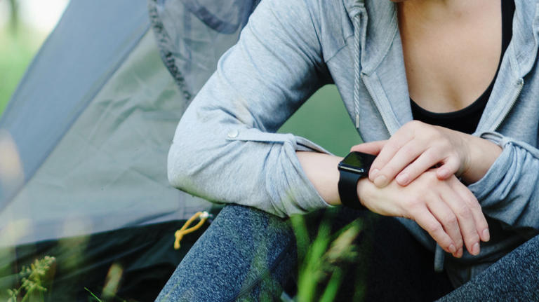 Person checking Apple Watch camping