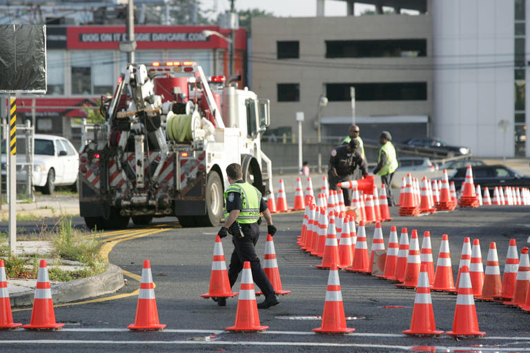 A Port Authority Police Officer and Maintenance Crews remove the traffic cones opening all lanes and toll booths to the George Washington Bridge at the intersection of Martha Washington Way and Bruce Reynolds Blvd Friday morning, September 13, 2013 at 8AM.