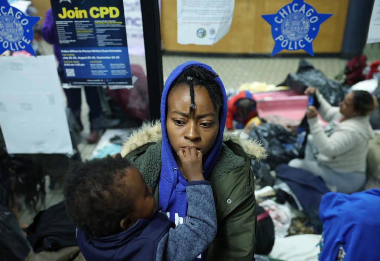 Jessica Wilson is fed a cookie by her son, Jacobie, 2, in the entryway to Chicago's District 3 police station on Cottage Grove Avenue on Oct. 13, 2023. Wilson and her son had been living out of the station with migrants, mostly from Venezuela.