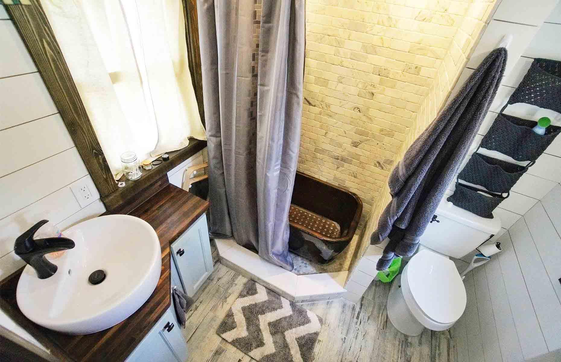 <p>Situated at the rear of the tiny house, what the bathroom lacks in size, it more than makes up for in style. Lined with tumbled Italian marble tiles, the walk-in rainfall shower takes centre stage, while nifty design details like the corner vanity make the best use of the available space. </p>