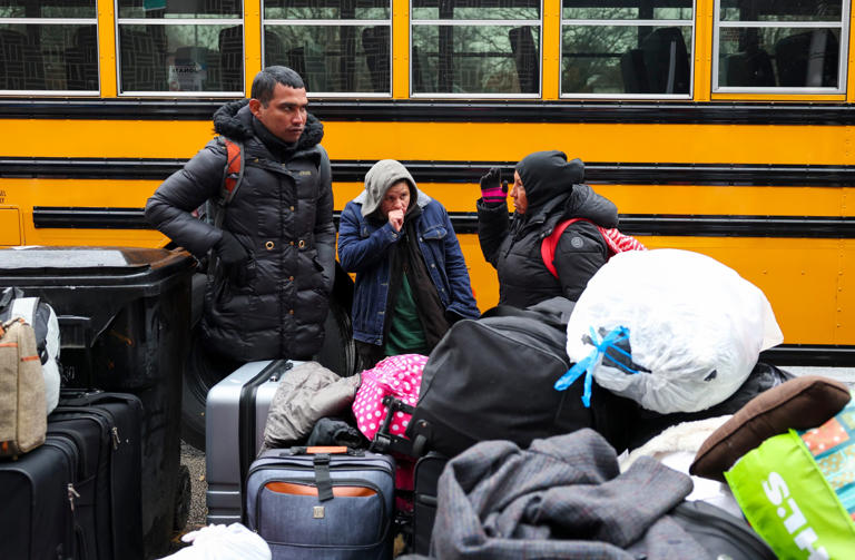 Migrants wait with their belongings to board a bus and be moved from outside of the 8th District police station in the Chicago Lawn neighborhood on Nov. 21, 2023.