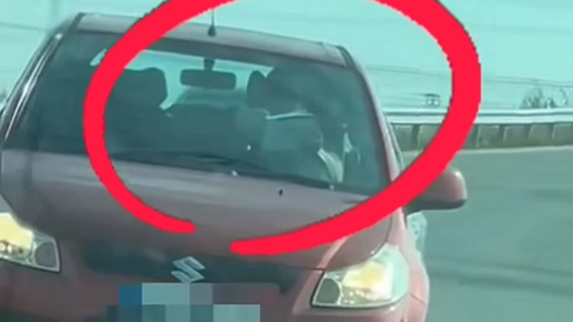 videón, ahogy vezetés közben könyvet olvasgat egy suzuki sofőrje
