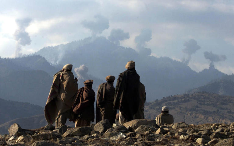 Afghan fighters watch explosions from US bombings in the Tora Bora mountains, 2001
