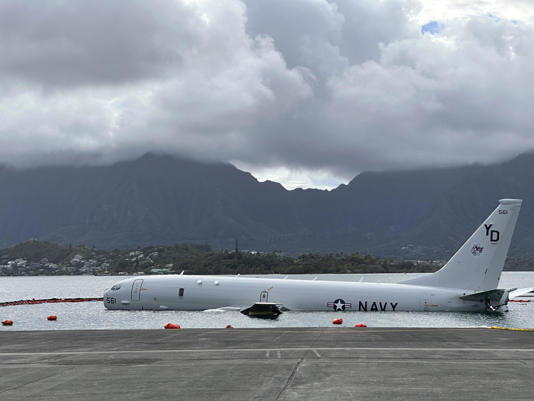 A Navy P-8A plane that overshot a runway at Marine Corps Base Hawaii and landed in shallow water offshore sits on a reef and sand in Kaneohe Bay, Hawaii, on Monday, Nov. 27, 2023. / Credit: Audrey McAvoy/AP