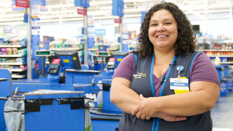 A Walmart associate stands in front of the checkout aisles. -lead