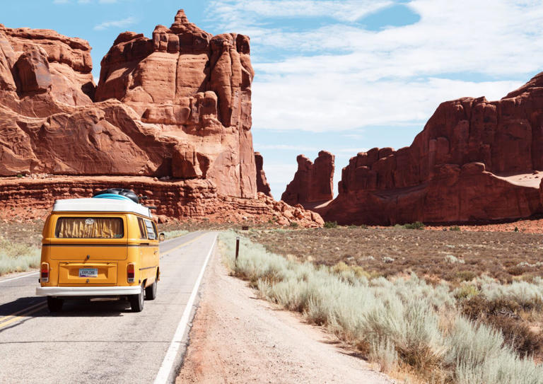 Road tripping can be boring if there is nothing to do. Check out these games that will make a road trip exciting. pictured: A yellow van moving down a road near a stunning canyon