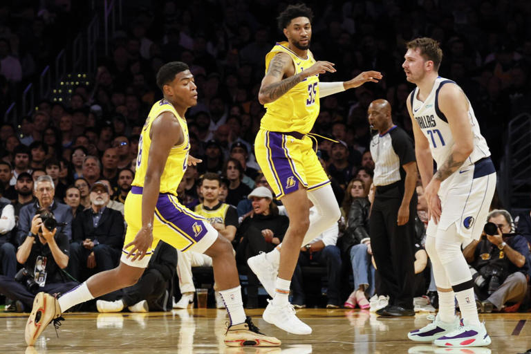 Lakers forward Christian Wood (35) attempts to cover Dallas Mavericks guard Luka Doncic (77) as Anthony Davis looks on Wednesday night at Crypto.Com Arena. ((Robert Gauthier / Los Angeles Times))
