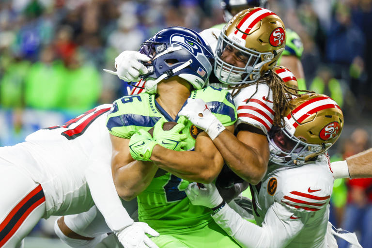 San Francisco 49ers linebacker Fred Warner (54) and linebacker Randy Gregory (5) tackle Seattle Seahawks running back Zach Charbonnet (26) on a rushing attempt. © Joe Nicholson, USA TODAY