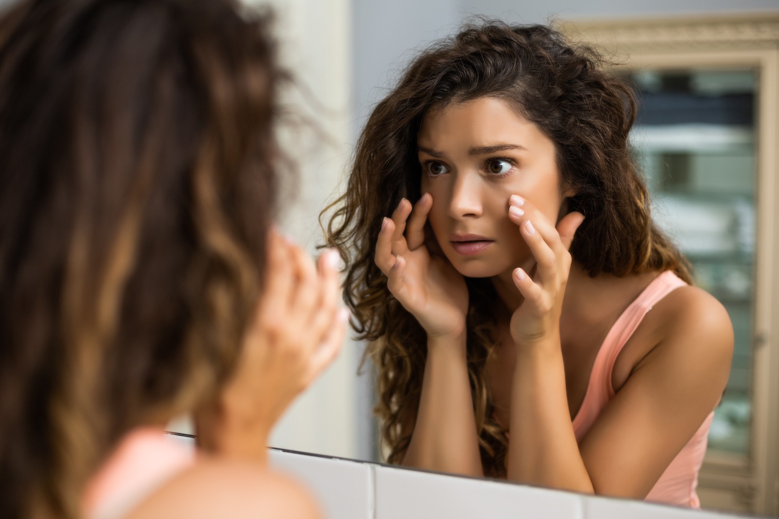 Jane looks worried she break the mirror. Looking for her. Woman look the right. Women look Horrified. Woman with short hair crying looking in the Mirror.