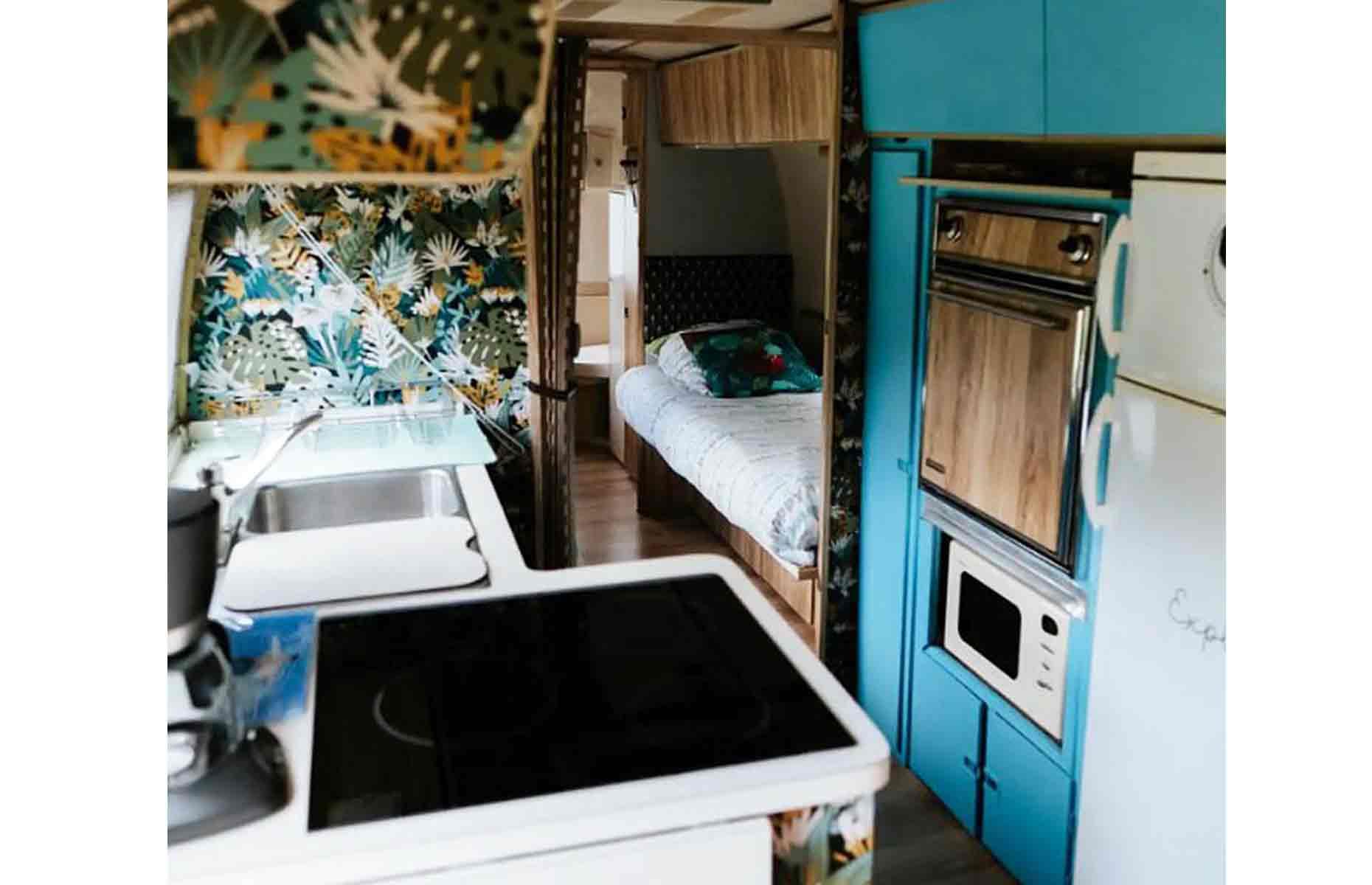 <p>Inside, the vintage Airstream has been kitted out to the very highest standard of modern luxury. The compact kitchen comes fully equipped with a hob, oven, microwave and sink, as well as a fun splashback and blue cupboards reminiscent of the vehicle’s 60s origins.</p>  <p>Remarkably, the tiny Airstream can sleep up to four, with a cosy alcove bed and a couch that folds out into another bed.</p>