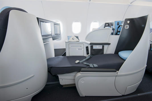 The seats, arranged two on each side of the aircraft, recline fully and are equipped with universal electrical outlets—plus fluffy pillows, quilted blankets, and noise-canceling headphones.